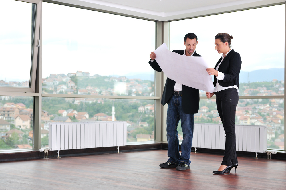 young architect group in big bright modern new apartment looking blueprints and building plans